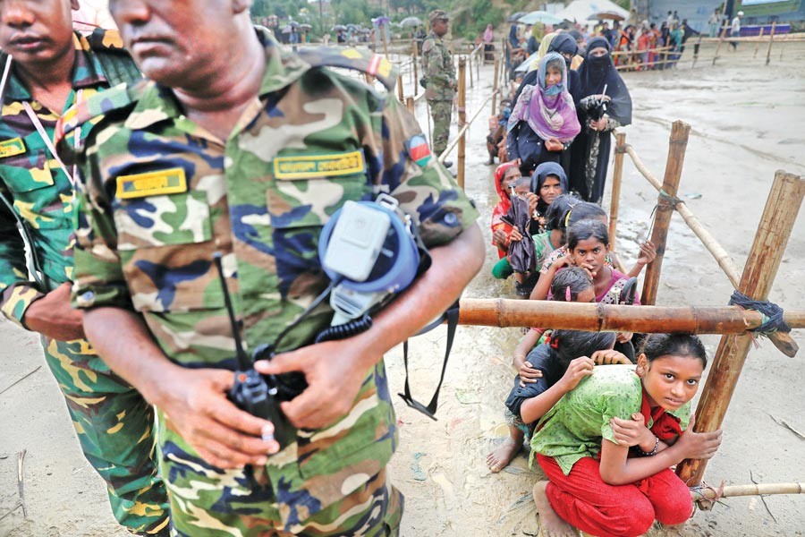 Rohingya refugees who earlier fled from Myanmar and took shelter at a camp in Cox's Bazar wait for aid on Sunday. — Reuters
