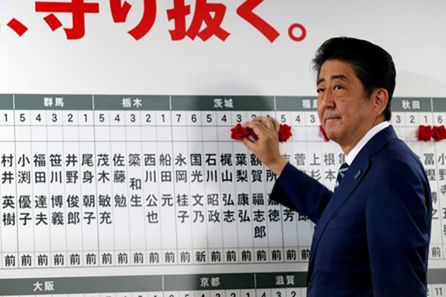 Japan's Prime Minister Shinzo Abe, leader of the Liberal Democratic Party (LDP), puts a rosette next to his name after the lower house election on Sunday. - Reuters