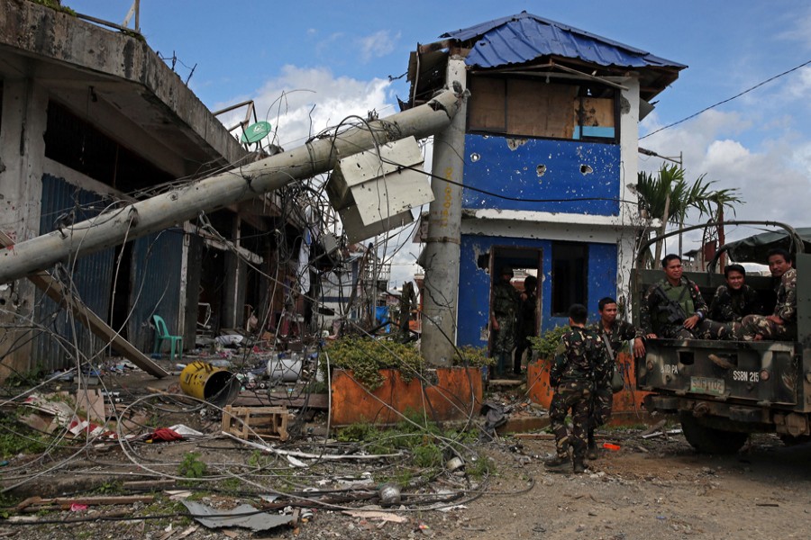 Soldiers stand guard in front of damaged buildings after government troops cleared the area from pro-Islamic State militant groups inside a war-torn area in Bangolo town of Marawi City, Philippines, on Monday. — Reuters