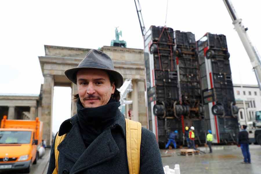 BERLIN: German-Syrian artist Manaf Halbouni poses in front of his installation "Monument" in front of the Brandenburg Gate in Berlin on Friday. — Reuters