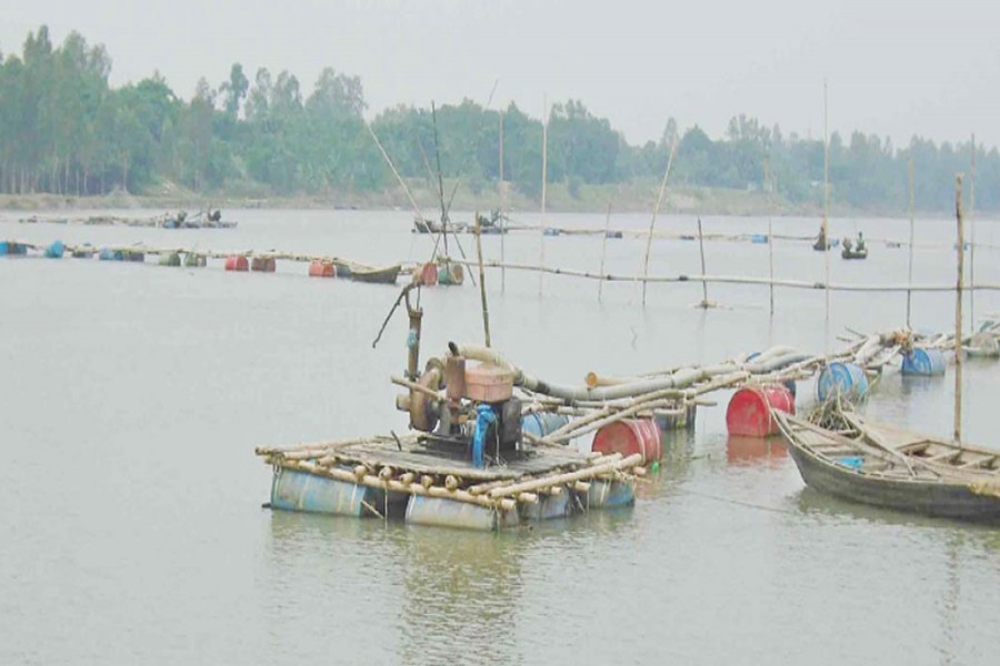 Some influential people are lifting sand from the Atrai river under Manda upazila in Naogaon defying an official ban. The snap was taken on Wednesday. — FE Photo
