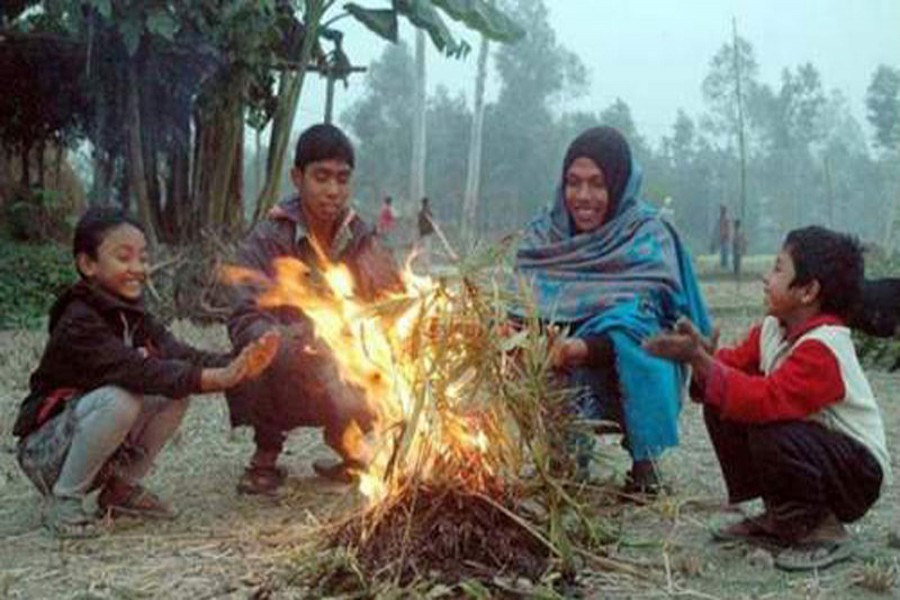 Cold-hit people sit by a fire to warm themselves at a slum of Rajshahi on Tuesday morning. — FE photo