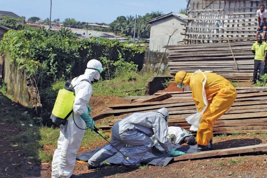 Health workers remove the body a woman who died from the Ebola virus in the Aberdeen district of Freetown, Sierra Leone, on October 14, 2014. —Photo: Reuters