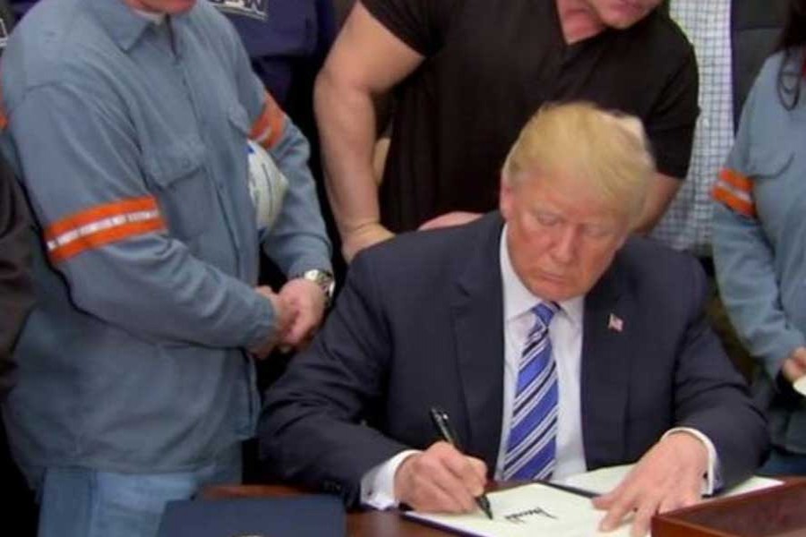 US President Donald Trump signs a presidential proclamation placing tariffs on steel and aluminum imports while surrounded by workers from the steel and aluminum industries at the White House in Washington on March 08, 2018. — Photo: Reuters