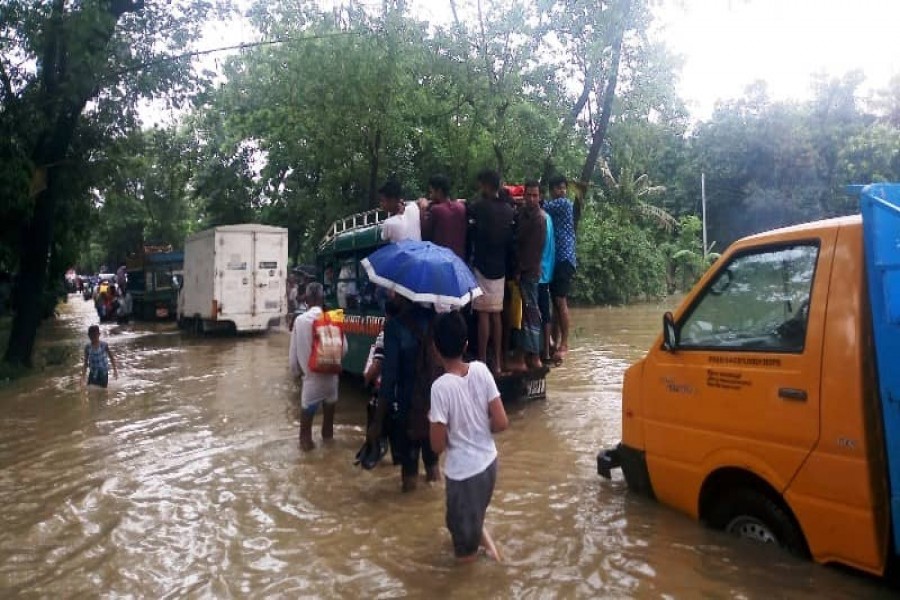 People wading through knee-deep water on a road in Raoza of Chattogram on Tuesday -Photo: UNB