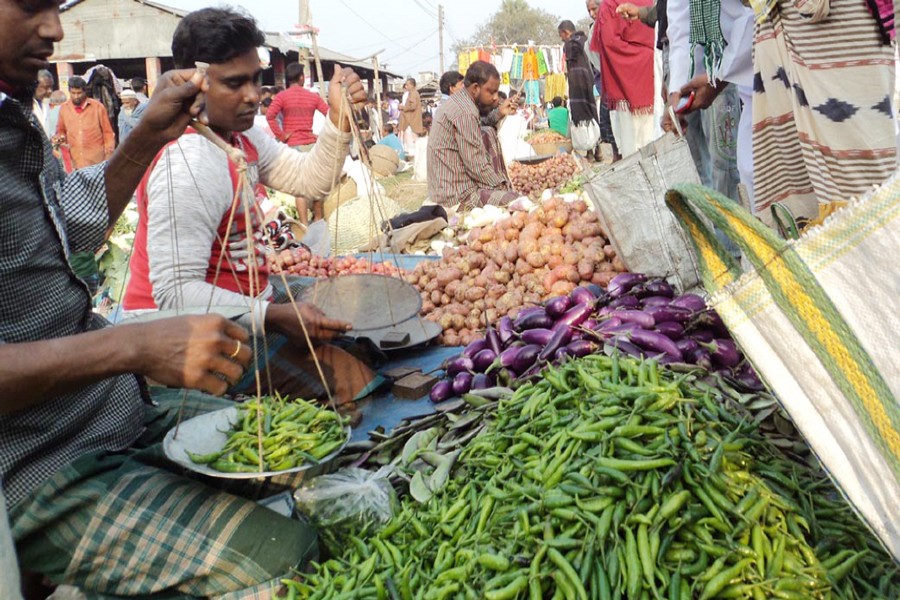 A seller weighing green chilli at Madhupur Bazar in Khetlal upazila of Joypurhat on Sunday — FE Photo