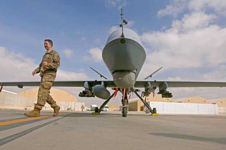 US service member passing in front of an MQ-9 Reaper drone — Reuters
