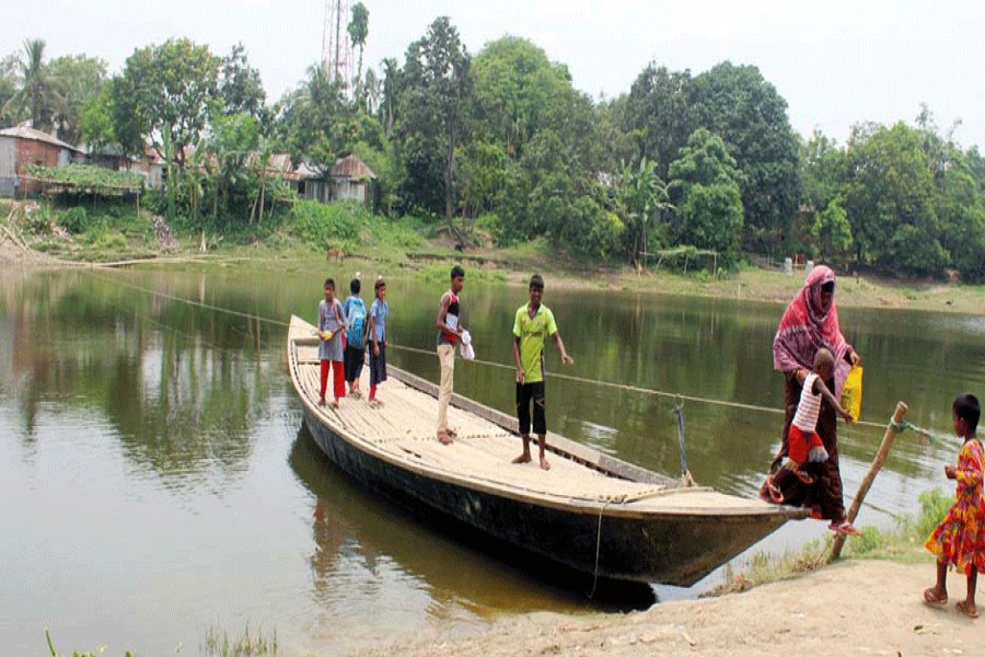 Villagers crossing the Nandakuja river by a boat at Mollabazar Terminal under Gurudaspur upazila in Rajshahi on Sunday pulling a rope in absence of a boatman — FE photo