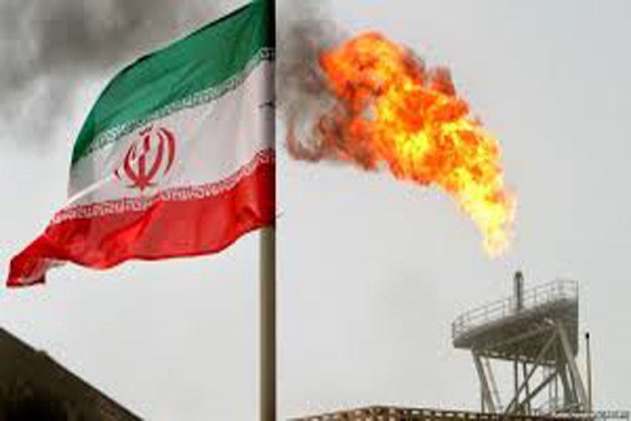 A gas flare on an oil production platform in the Soroush oilfields is seen alongside an Iranian flag in Iran — Reuters