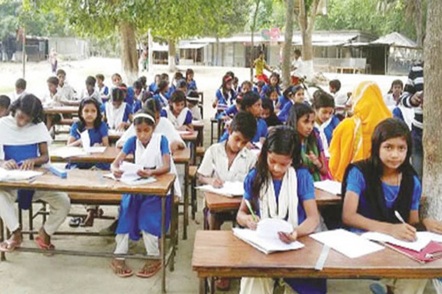 Students of Government Primary School in Manairi union under Atrai upazila of Naogaon sitting for a examination under the open sky — FE Photo