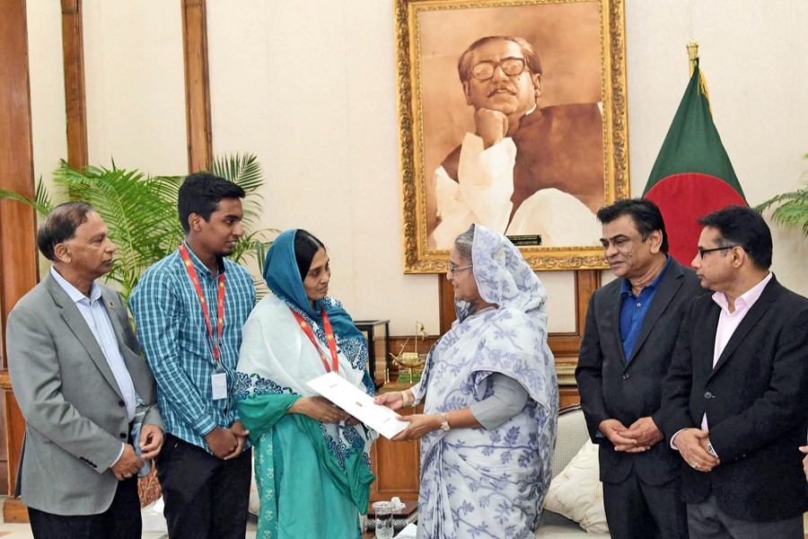 Prime Minister Sheikh Hasina handing over the papers of residential flats to the families of two former national footballers and a hockey player at a function held at the Prime Minister's official residence Ganobhaban in the city on Thursday — PID