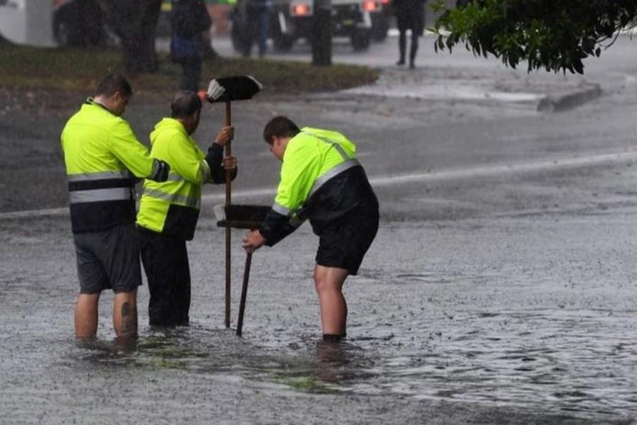 SYDNEY: Workers attempting to clear a drain in a water-logged road — EPA