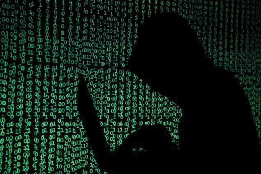 A hooded man holds a laptop computer as cyber code is projected on him in this illustration picture taken on May 13, 2017. — Photo: Reuters