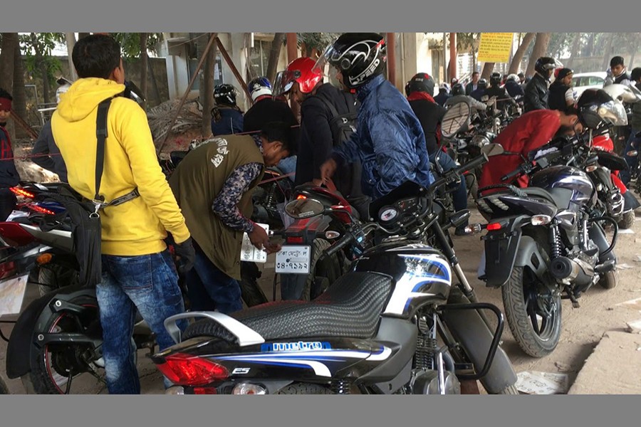 An employee of BRTA installs digital number plate on motorbikes. Image derived from Youtube