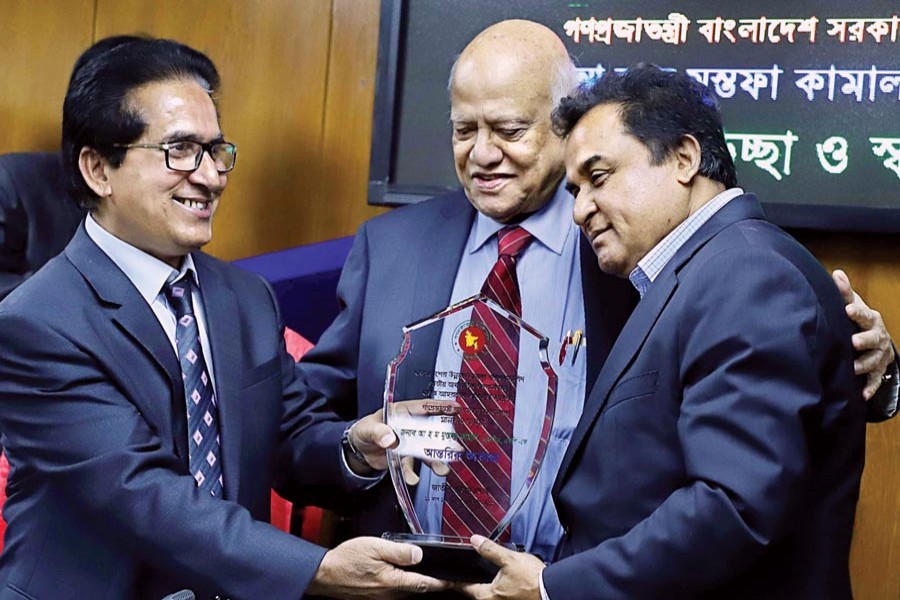 NBR Chairman Musharraf Hussain Bhuiyan presenting a crest to Finance Minister AHM Mustafa Kamal at the NBR office in the city on Thursday to welcome the incumbent minister and bid farewell to former Finance Minister AMA Muhith (Collected photo)