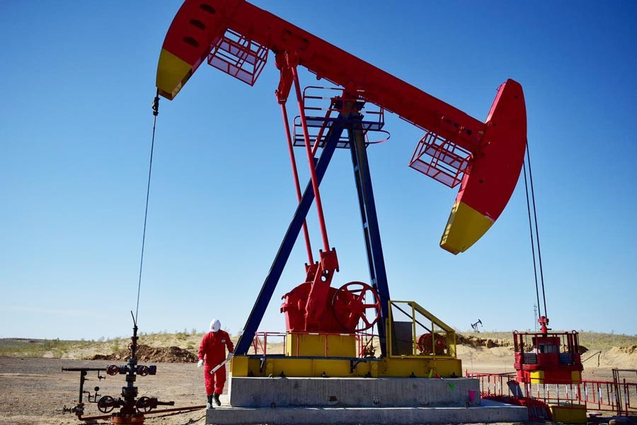 A PetroChina worker inspects a pump jack at an oil field in Tacheng, Xinjiang Uighur Autonomous Region, China — Reuters
