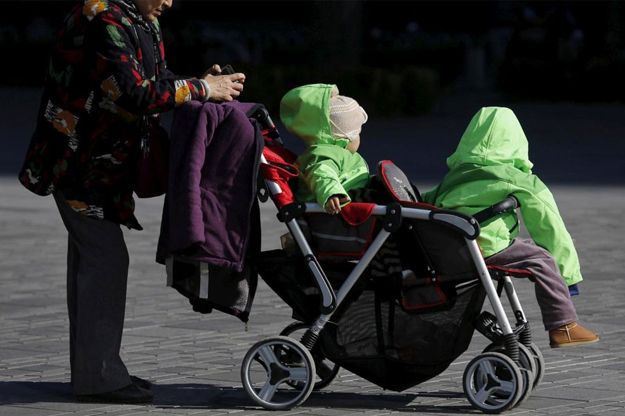 FILE PHOTO: An elderly woman pushes two babies in a stroller in Beijing, China October 30, 2015 - REUTERS/Kim Kyung-Hoon/File Photo