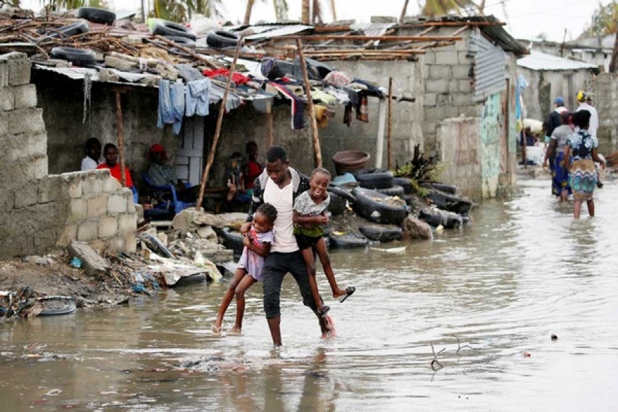 A man carries his children after Cyclone Idai at Praia Nova, in Beira, Mozambique, Mar 23, 2019. - Reuters