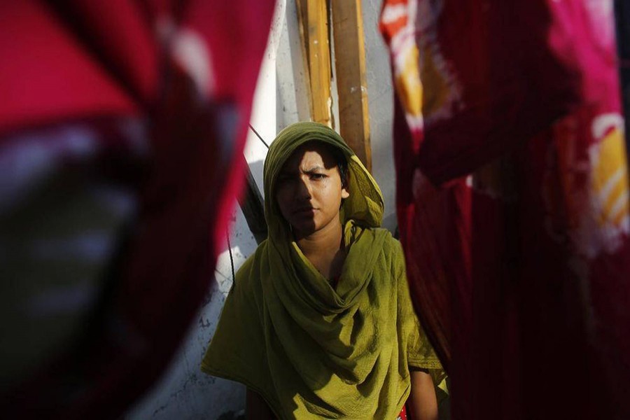 Khodeja, 25, who was rescued from the rubble of the collapsed Rana Plaza building, stands in front of her slum house in Savar. Khodeja is unable to work due to a spinal injury caused by the accident — Reuters/Files