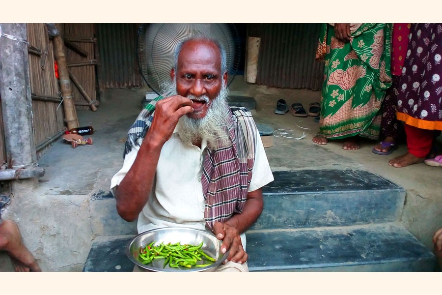Mobarak Mollah eating green chilli at his home — FE Photo