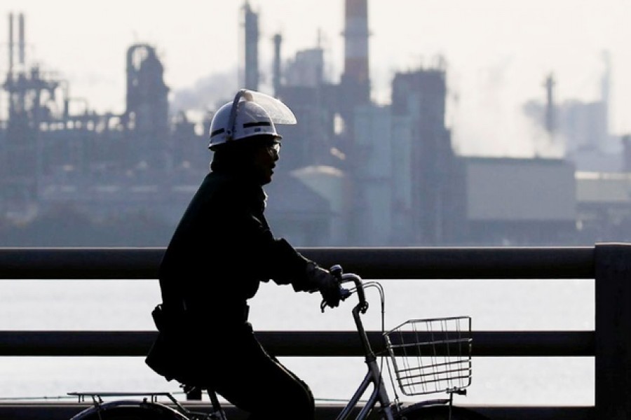 A worker cycles near a factory at the Keihin industrial zone in Kawasaki, Japan, November 15, 2017. Reuters/File Photo