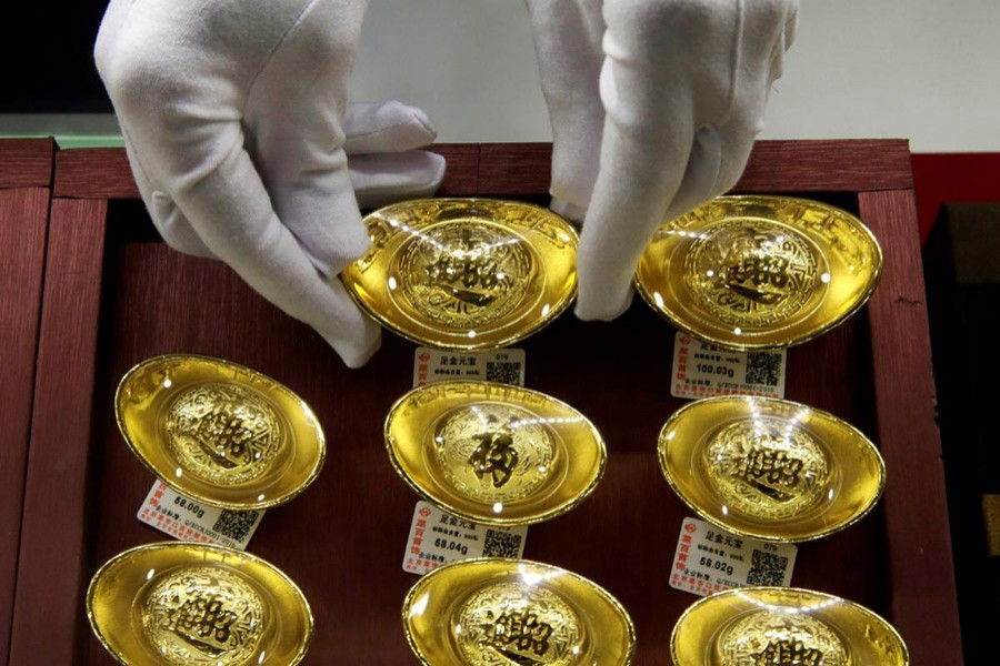 A sales assistant places gold ornaments at Caibai Jewelry store, in Beijing, China, August 6, 2019. Reuters/File Photo