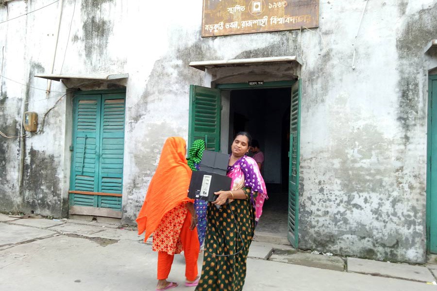 A family member of a RU employee who used to live in two rooms of the historical archaeological site of 'Boro Kuthi' is seen leaving the site with her belongings on Sunday — FE Photo
