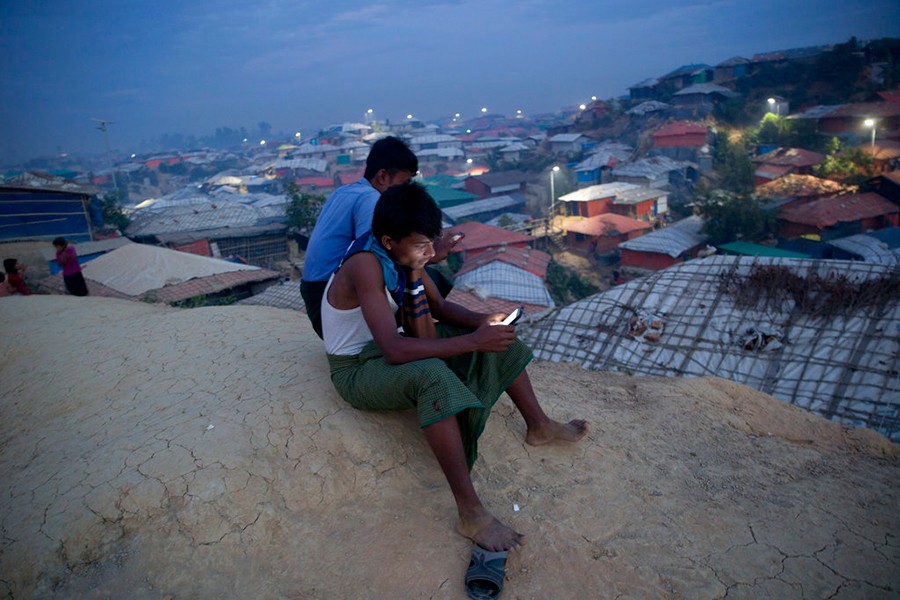 Rohingya Muslims use their mobile phones as they sit on a hill overlooking Balukhali refugee camp — AP/Files