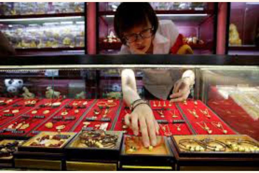 A sales assistant taking out gold ornaments for a customer at Caibai Jewelry store, in Beijing, China — Reuters