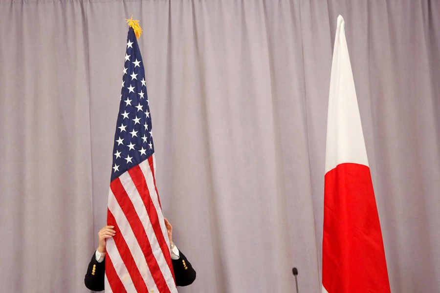 A worker adjusts the US flag before Japanese Prime Minister Shinzo Abe addresses media following a meeting with President-elect Donald Trump in Manhattan, New York, US, November 17, 2016. Reuters/Files