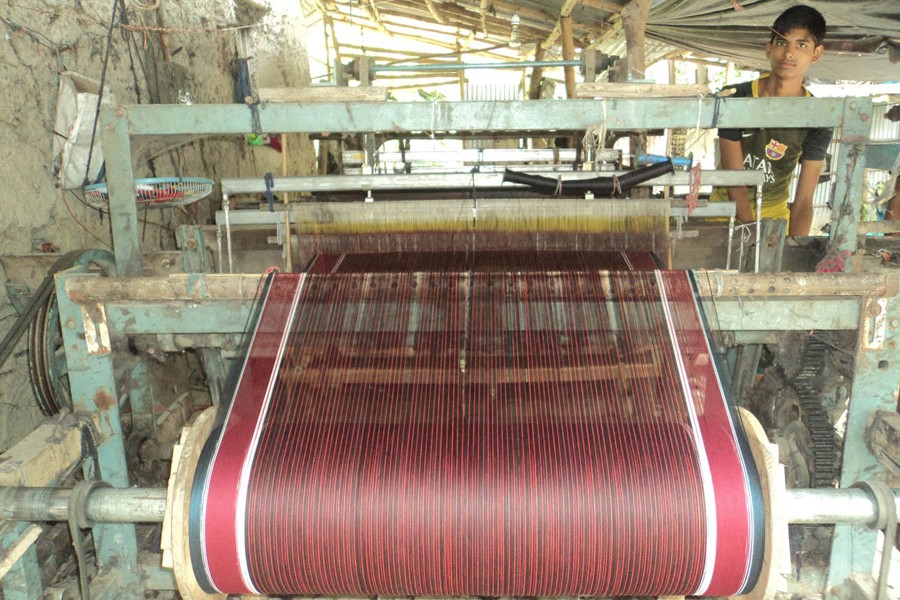 A young weaver weaving gamchha at a small factory in Adamdighi upazila of Bogura district — FE Photo