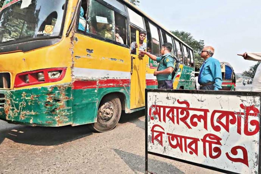 A policeman pulls over a bus on the Manik Mia Avenue in the city on Monday during a BRTA mobile court drive to check papers of the vehicle in order to see whether the driver is violating the Road Transport Act 2018 — FE photo