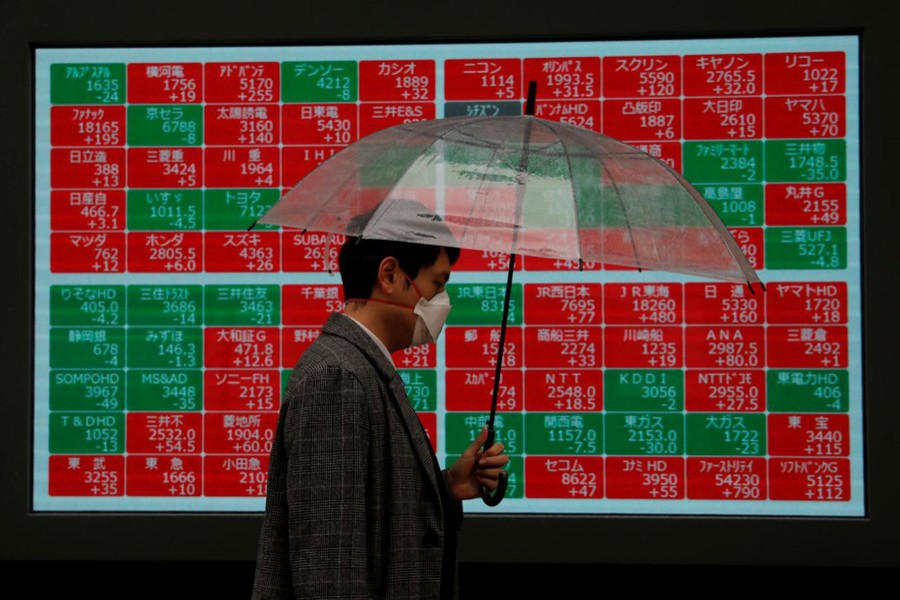 A visitor wearing protective face mask, following an outbreak of the coronavirus, walks past in front of a stock quotation board outside a brokerage in Tokyo, Japan, March 02, 2020 — Reuters
