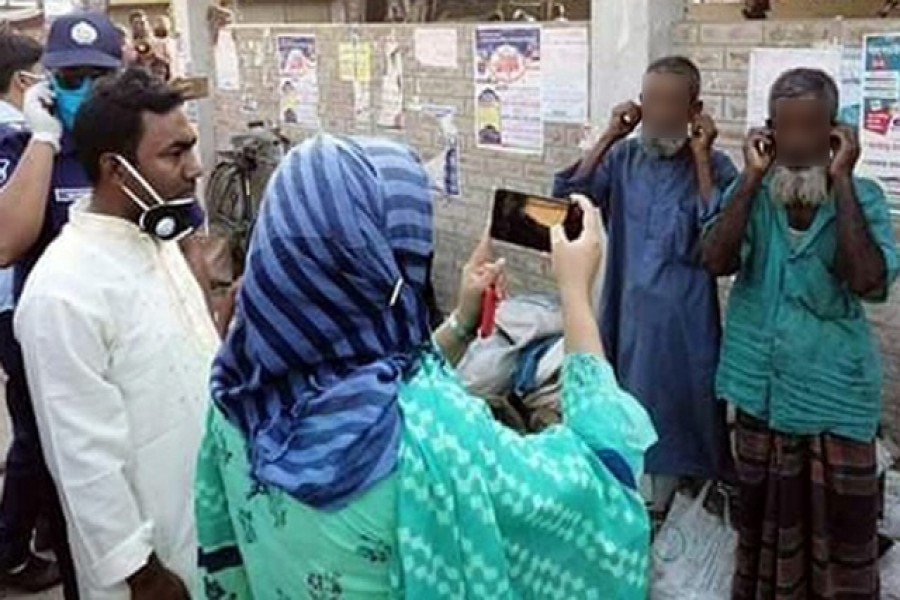 Moniranpur assistant commissioner, or AC, (land) Sayeema recording on her mobile phone two elderly men pulling their ears in a form of punishment handed down by her for their failure to wear masks during the coronavirus outbreak. — Photo Collected