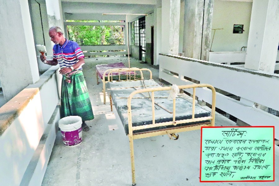 A worker putting a coat of paint on walls of Railway General Hospital in the city on Saturday while a notice in the hospital staircase (inset) says that it was yet to be ready for coronavirus treatment — FE photo by Shafiqul Alam