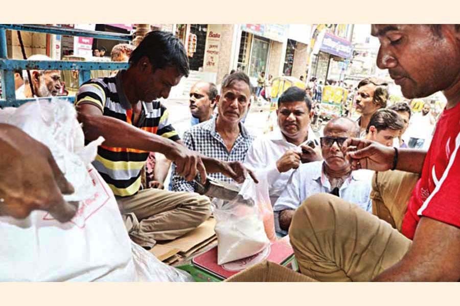 Few consumers buying essential items from a truck posted at Shahbagh crossing in the city by the TCB dealers on Monday. Though lentil and onion were listed in the banner, the consumers did not get the items — FE Photo
