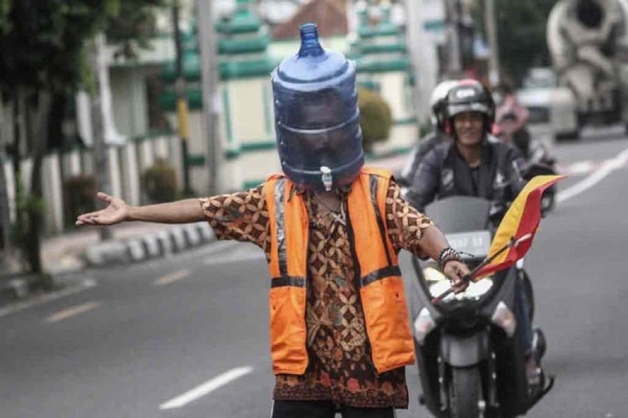Ali Akbar, 52, a parking attendant, uses a plastic bottle for a face mask amid the coronavirus disease (COVID-19) outbreak in Yogyakarta, Indonesia, Apr 15, 2020. REUTERS