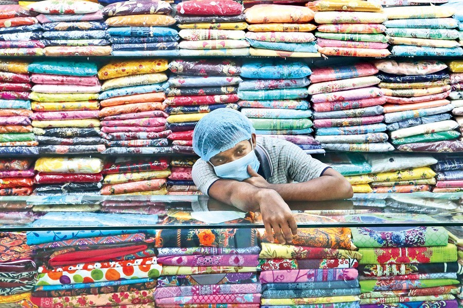 A salesman at the city’s Mouchak Market passes idle time on Tuesday in the absence of customers amid the Covid-19 pandemic — FE photo