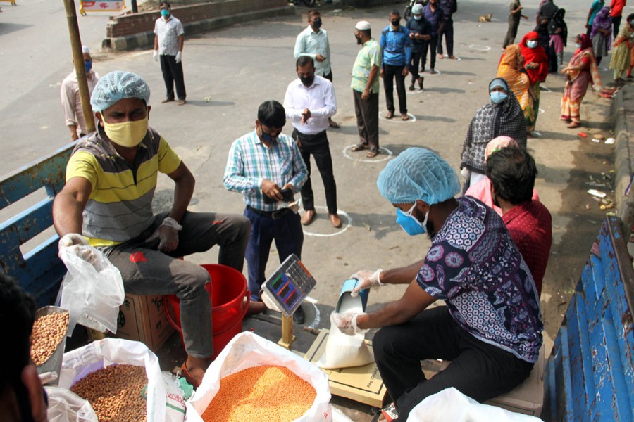 People, wearing face masks and maintaining social distancing, queue up to buy essentials from a TCB sale point in the capital — Focus Bangla/Files
