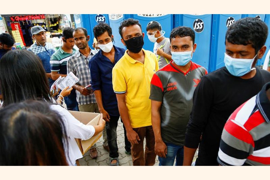 Migrant workers, mostly from Bangladesh, queue to collect free masks and get their temperatures taken in Singapore — Reuters