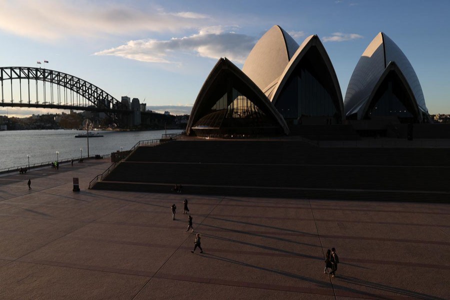 People are seen walking in front of the Sydney Opera House and Sydney Harbour Bridge following the easing of restrictions implemented to curb the spread of the coronavirus disease (COVID-19) in Sydney, Australia, June 23, 2020. REUTERS/Loren Elliott/File photo