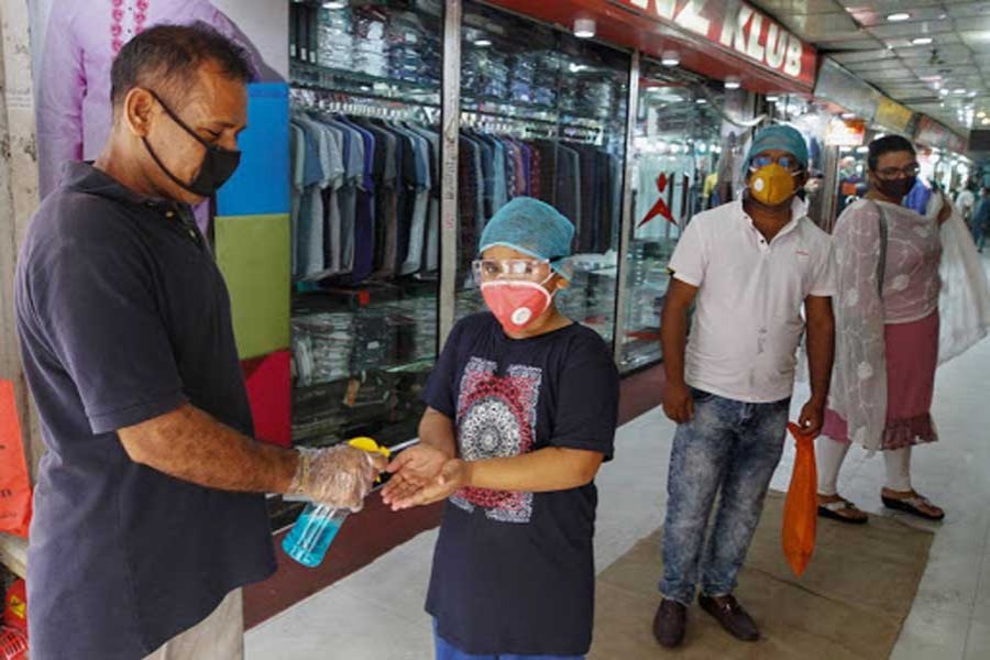 A staff gives a child hand sanitizer at a reopened market in Dhaka last year —Xinhua photo