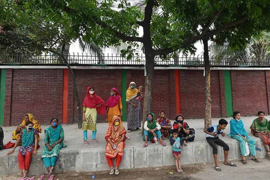 Low-income people hit hard by Covid-19 outbreak wait for collecting relief materials amid a shutdown in Dhaka. —Xinhua Photo