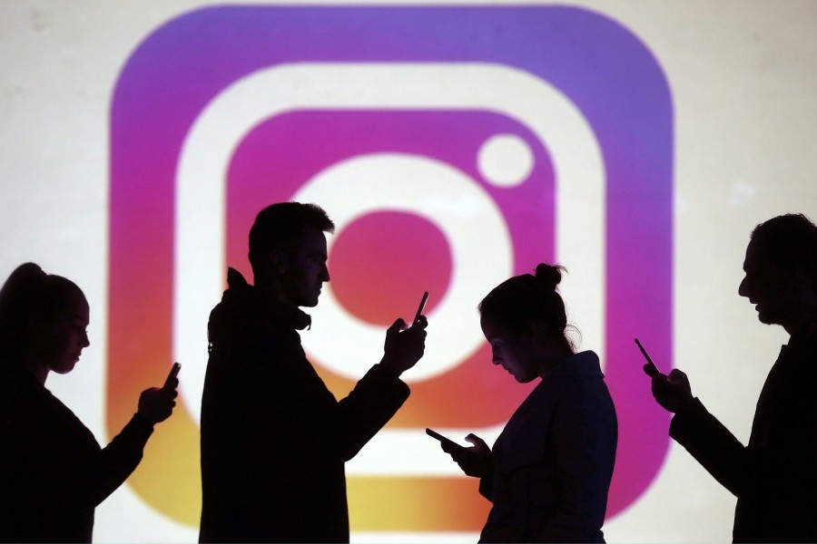 Silhouettes of mobile users are seen next to a screen projection of Instagram logo in this picture illustration - Reuters