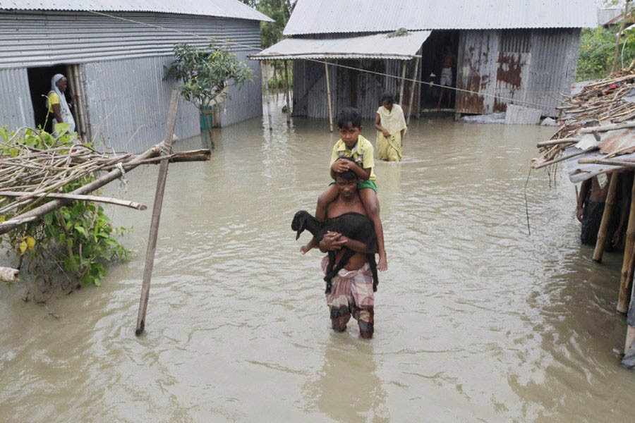 Bangladesh is vulnerable to climate change. The July 2, 2002, photo shows that people wade through flood water in search of a dry ground in Jamalpur, Bangladesh. —Xinhua Photo